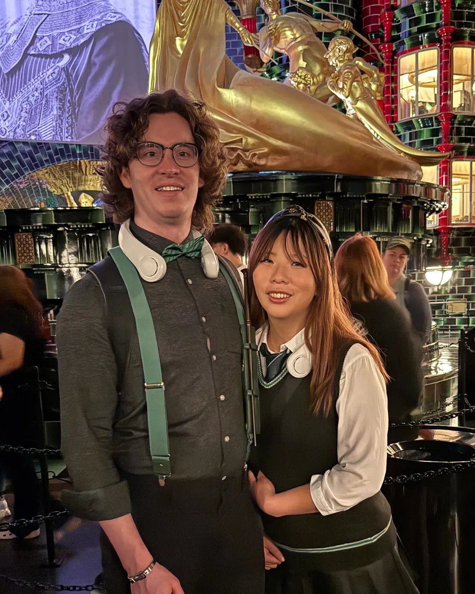 Jason and a friend, dressed up and smiling, in front of a giant gold statue.
